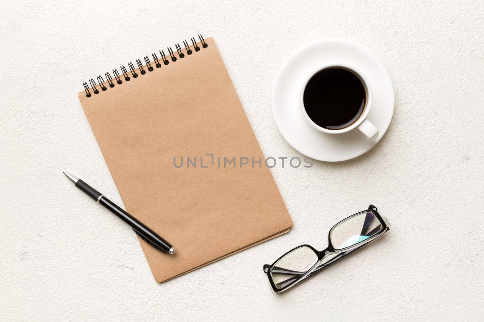 Modern office desk table with notebook and other supplies with cup of coffee. Blank notebook page for you design. Top view, flat lay.