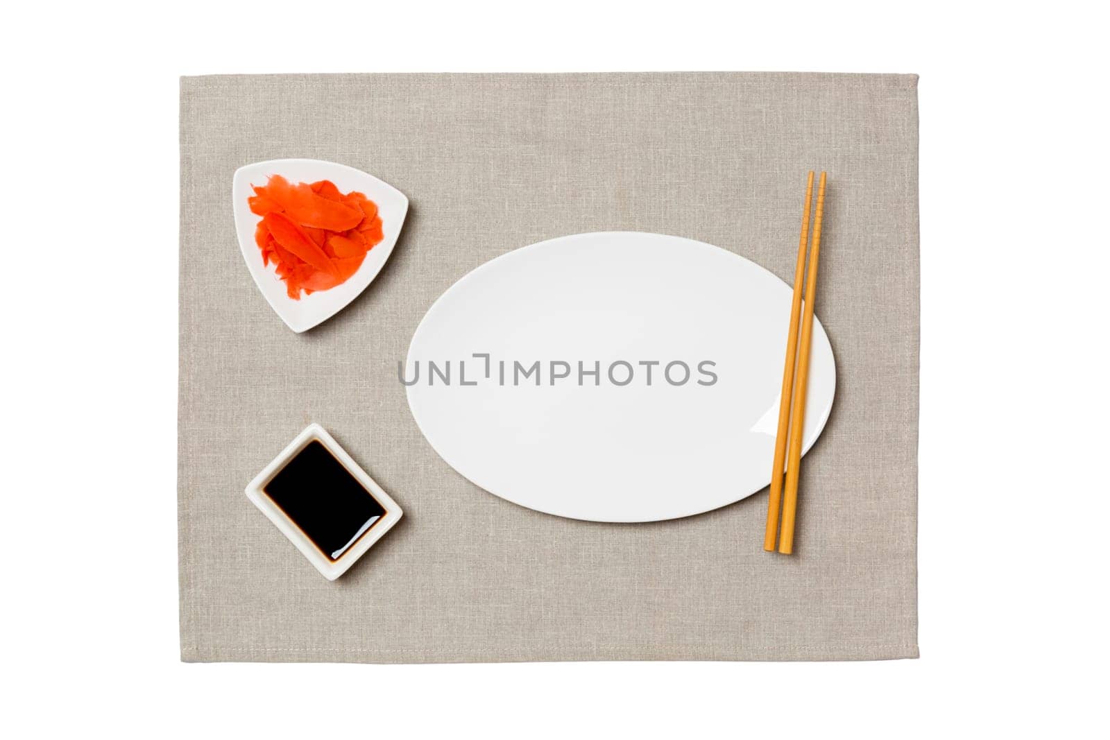 Empty oval white plate with chopsticks for sushi, ginger and soy sauce on grey napkin background. Top view with copy space for you design by Snegok1967