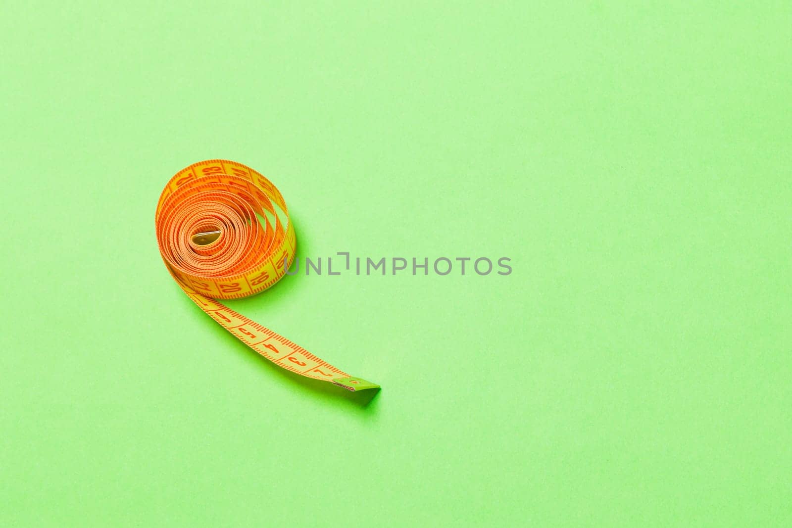 Tangled measuring tape with space for your idea. Sewing and tailor concept on green background.