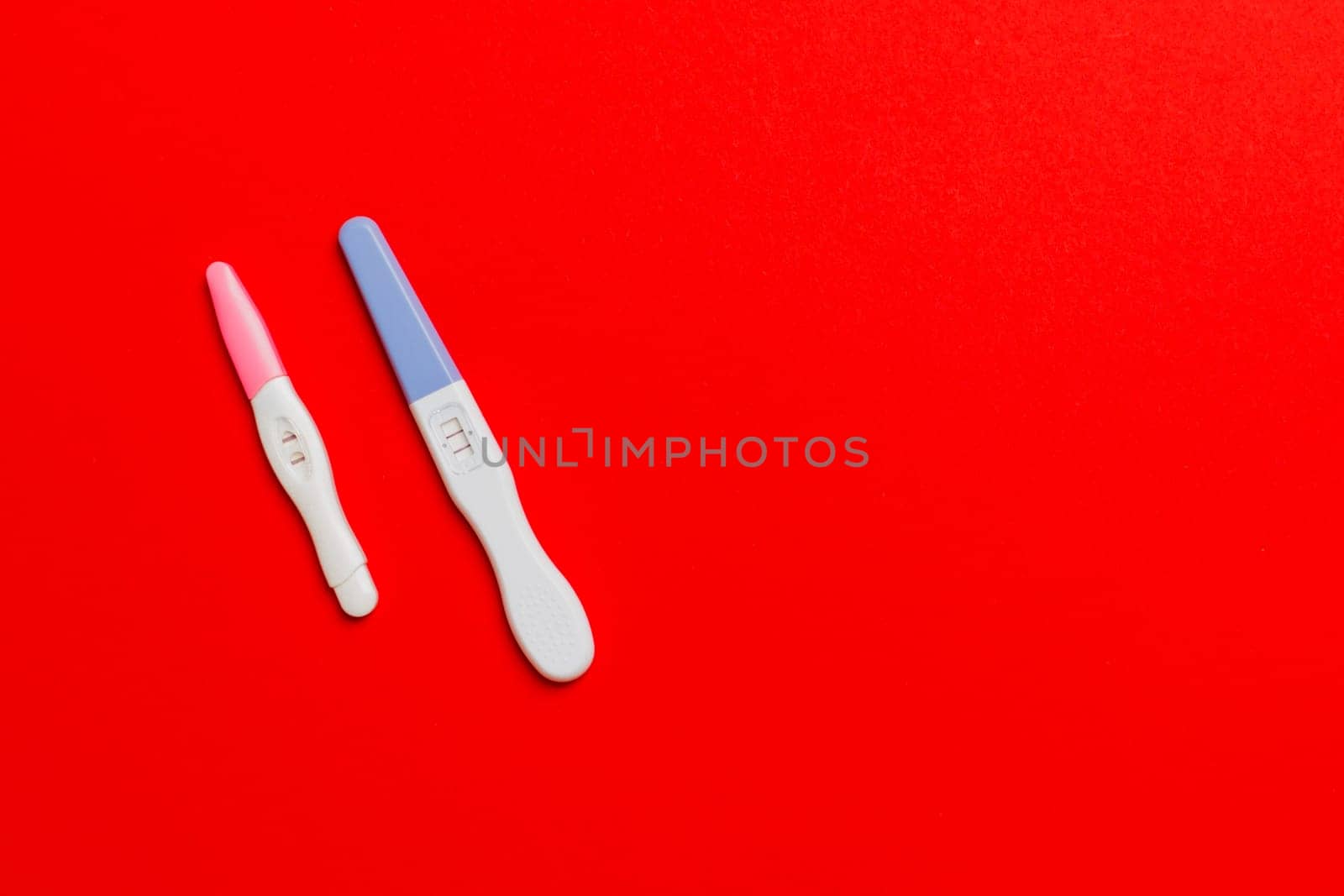 Colored Pregnancy test on colored background, top view with copy space.