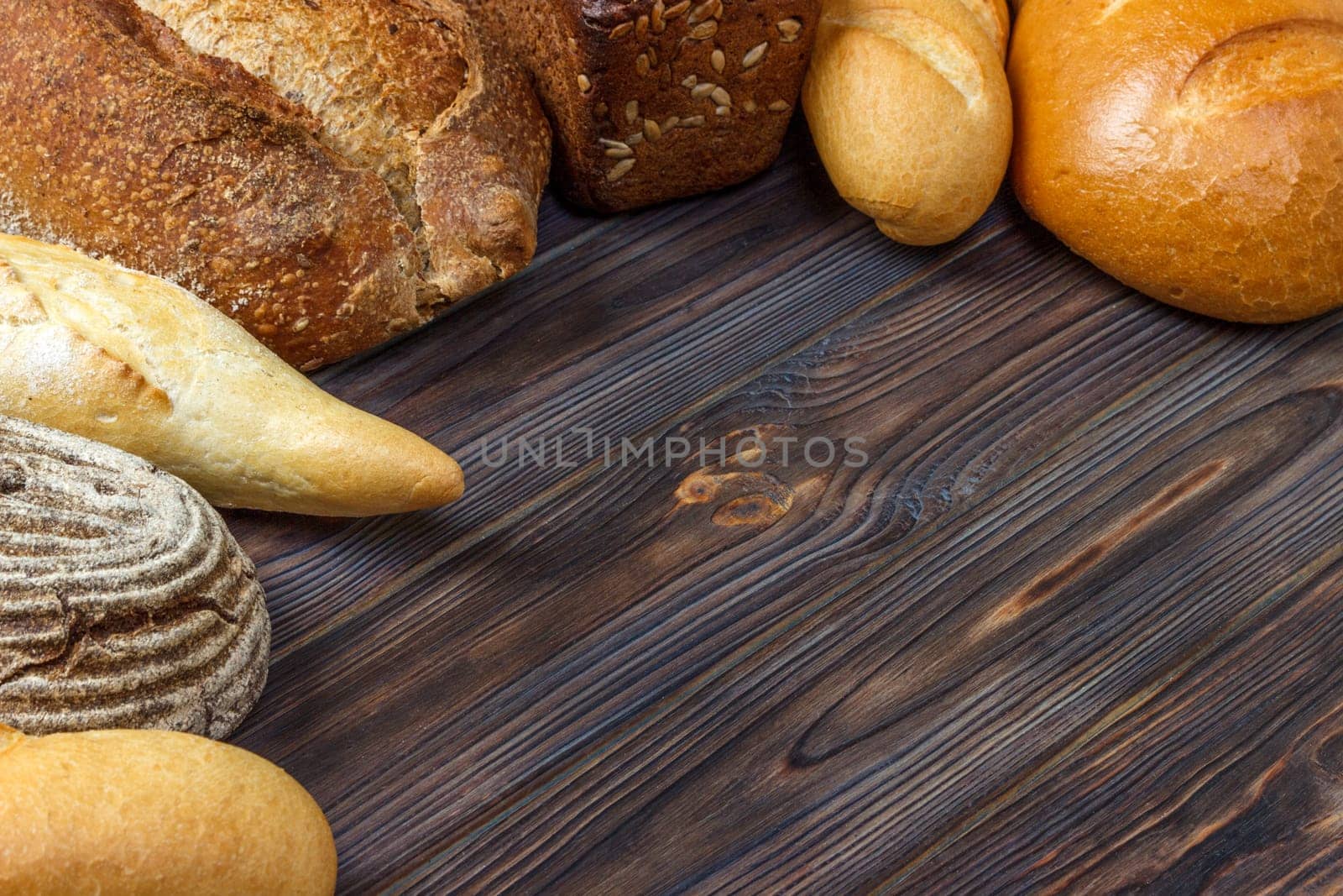 Bakery background, bread assortment on black wooden backdrop. Top view with copy space.