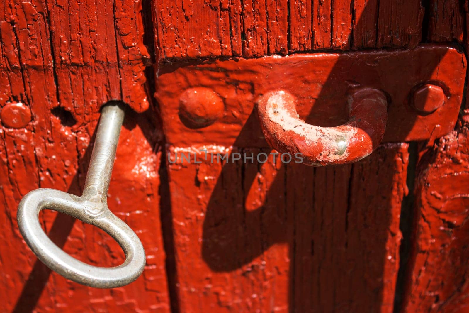 Antique iron key from the gate in the old red wooden gate.