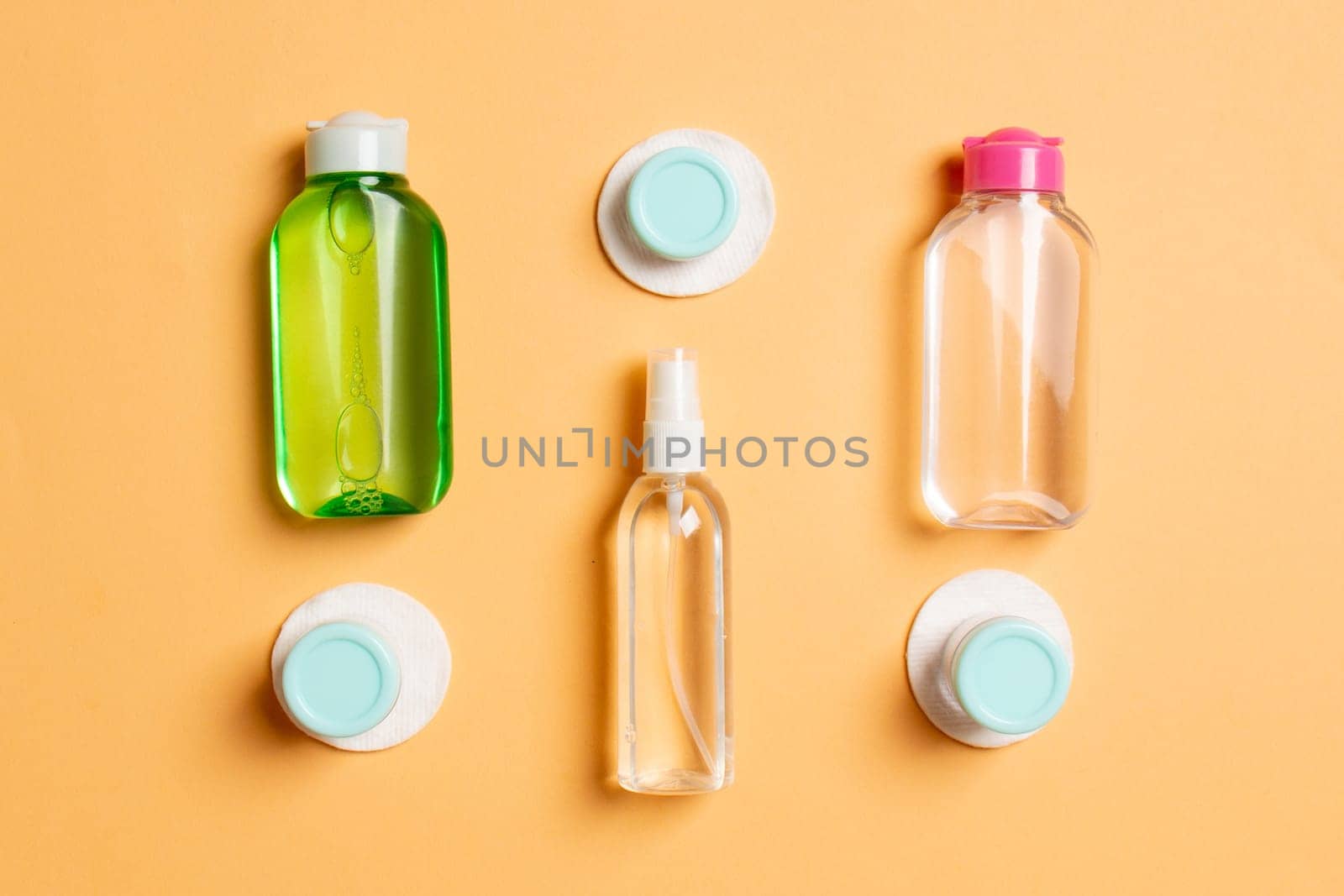 Set of travel size cosmetic bottles on colored background. Flat lay of cream jars. Top view of bodycare style concept by Snegok1967