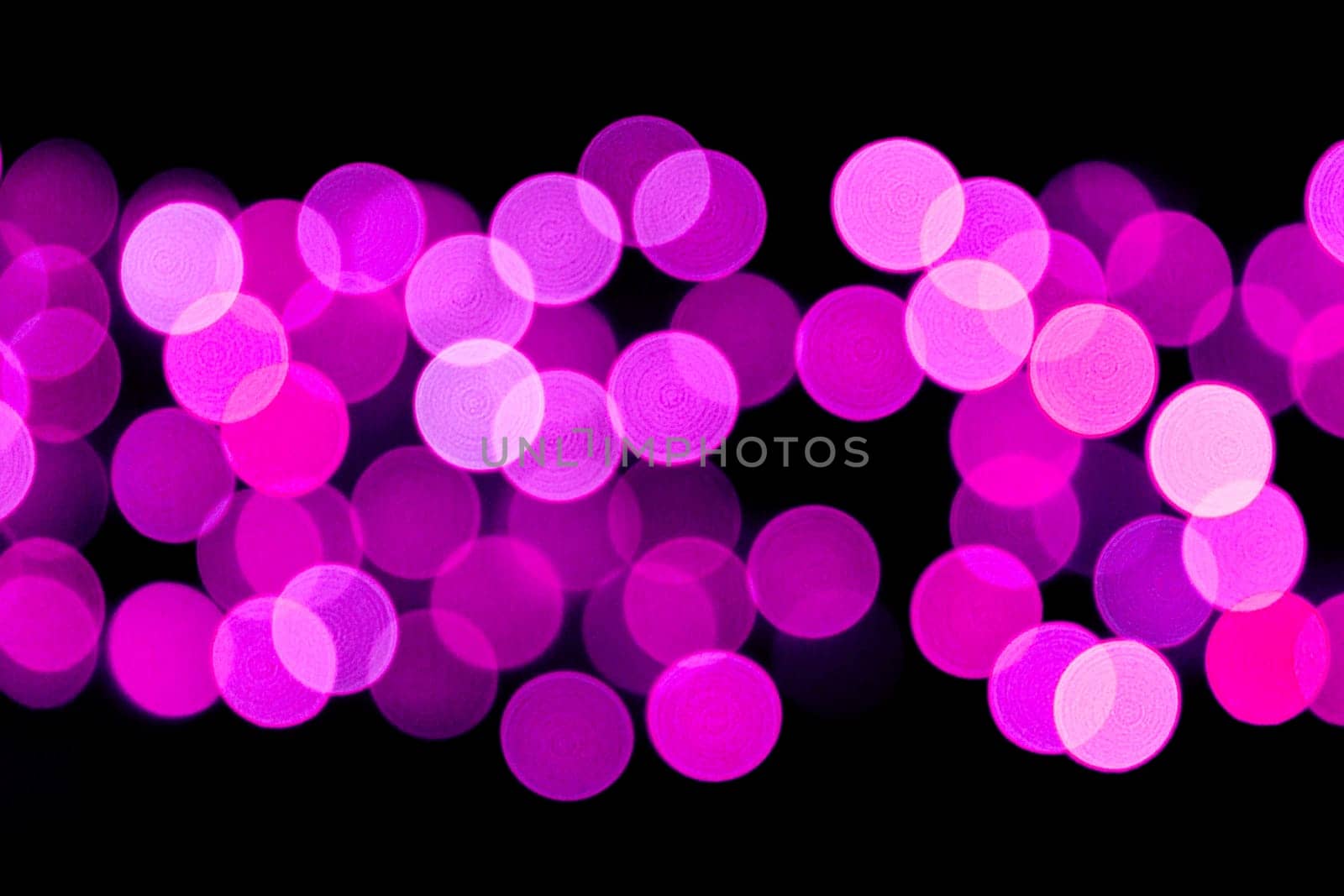 Unfocused abstract purple bokeh on black background. defocused and blurred many round light.