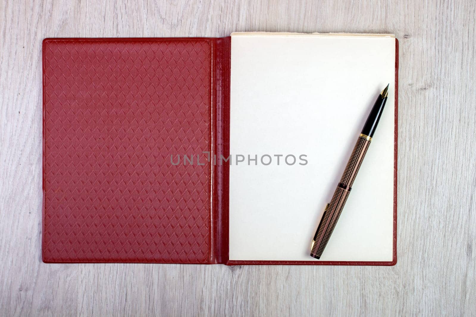 An Open Notebook With White Pages And Gold Fountain Pen On Wood Table. Overhead View