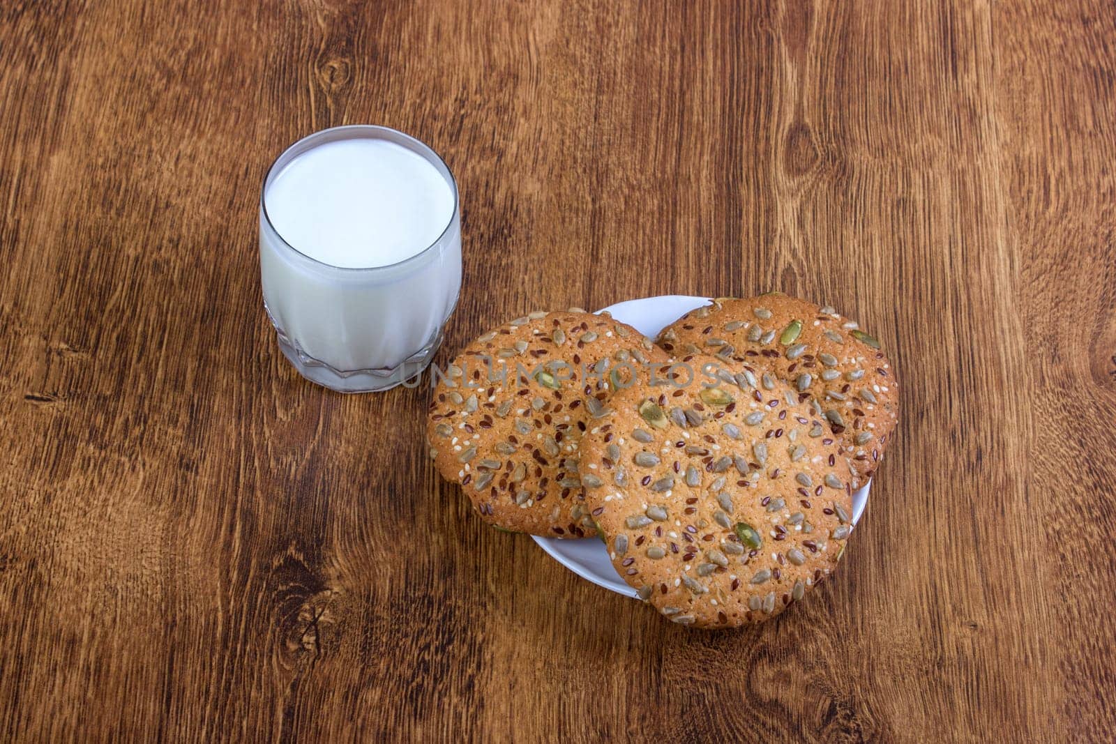 The composition of biscuits and a glass jar with milk. Cookies and milk white yogurt, on a white background with reflection. Tasty yellow brown cookies. Yogurt and oatmeal cookies.