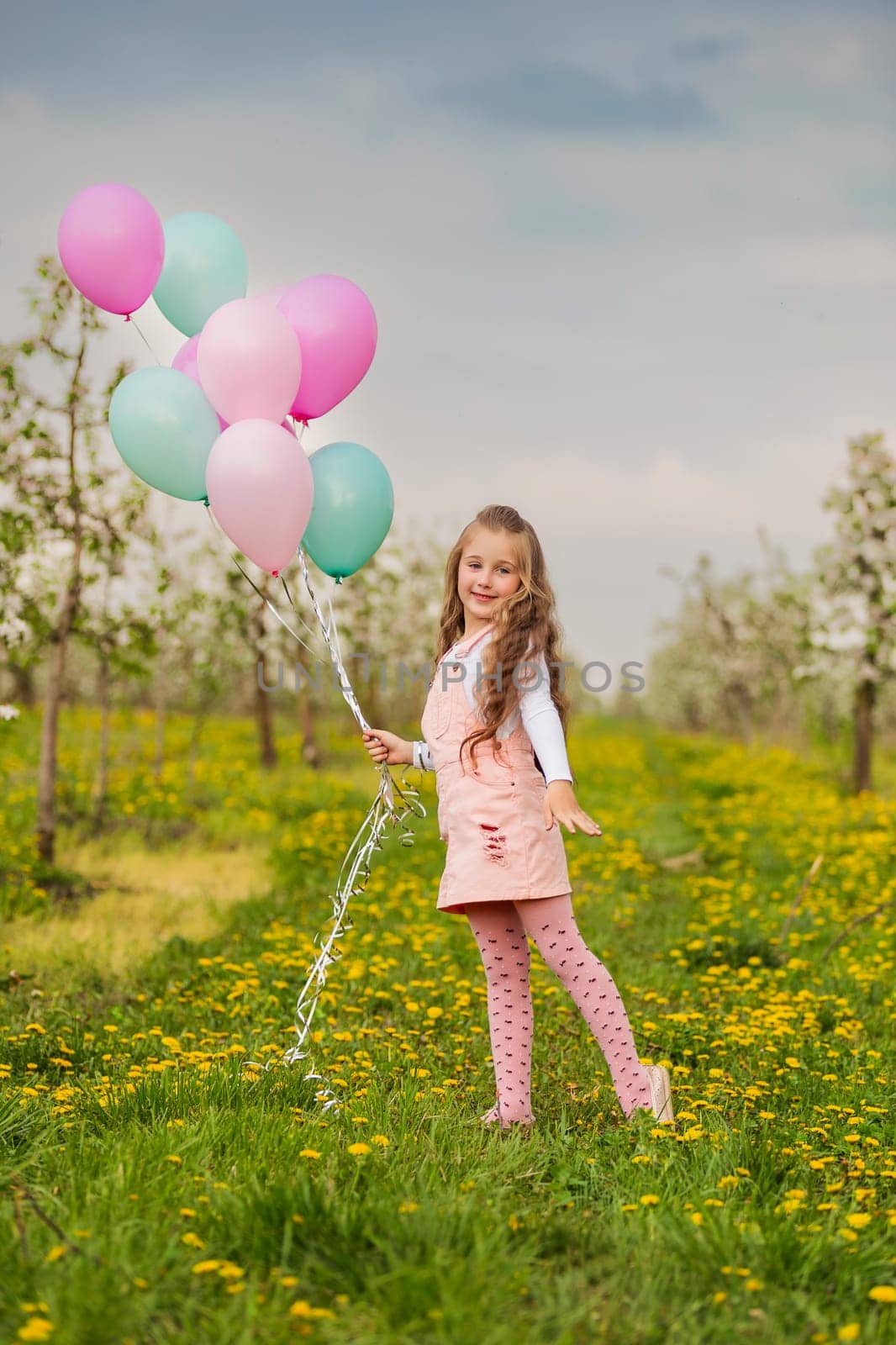 girl with colorful balloons in a blooming garden with trees