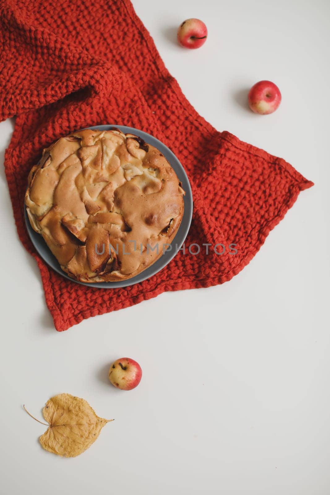 Slice of apple pie on a plate with apples on white table background