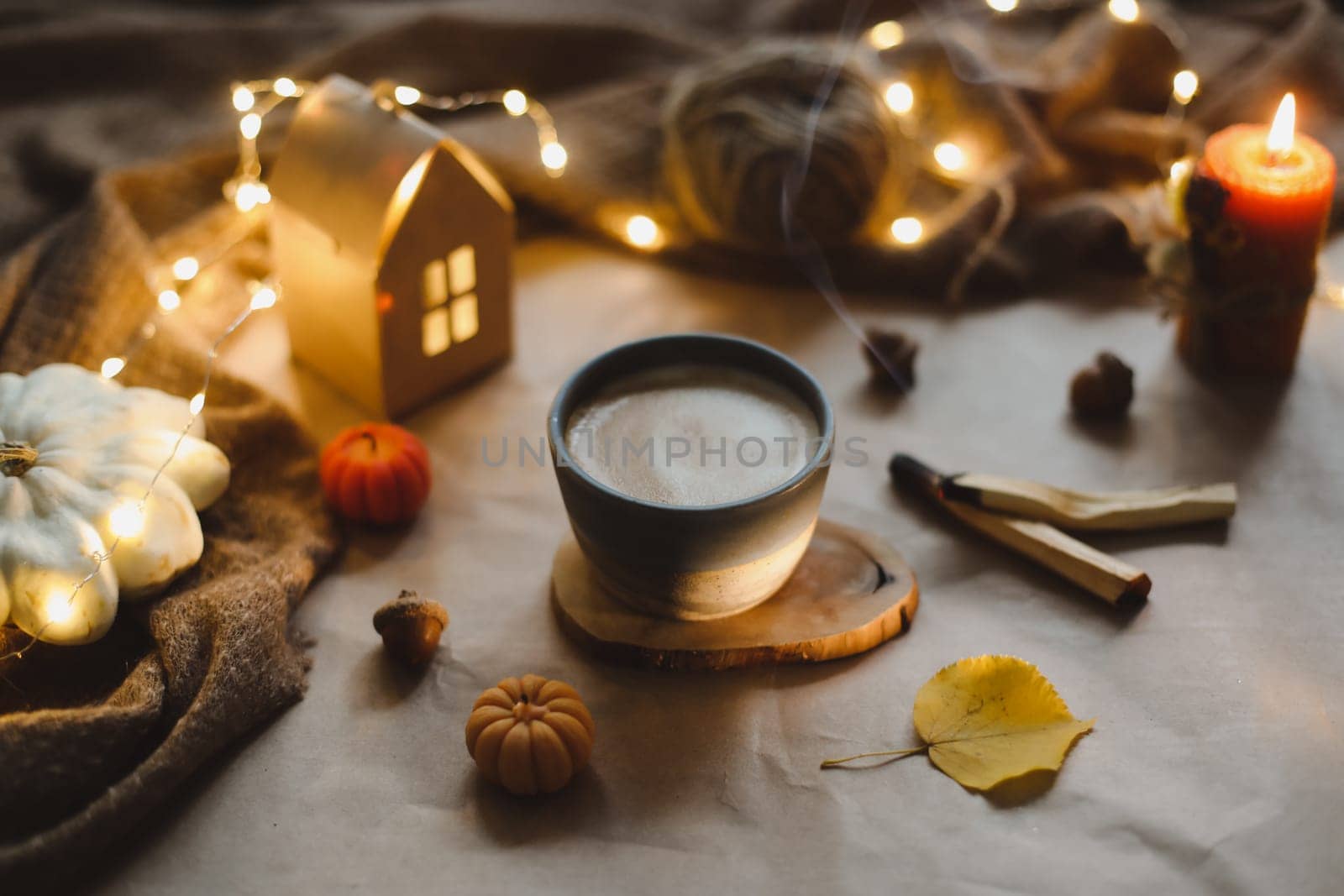 Autumn still life details in cozy home interior with a cup, candles, plaid. Hygge home decor. Halloween and Thanksgiving concept. Autumn banner