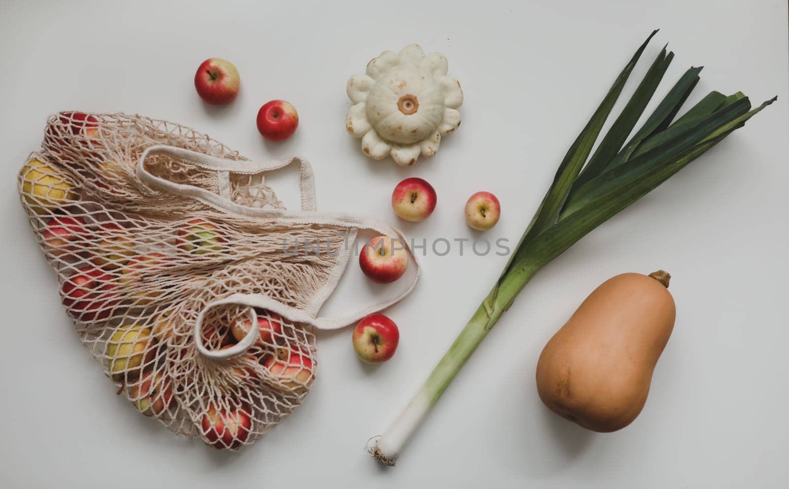 autumn harvest with pumpkin, sqush, apples in a eco mesh shopping bag. zero waste, no plastic