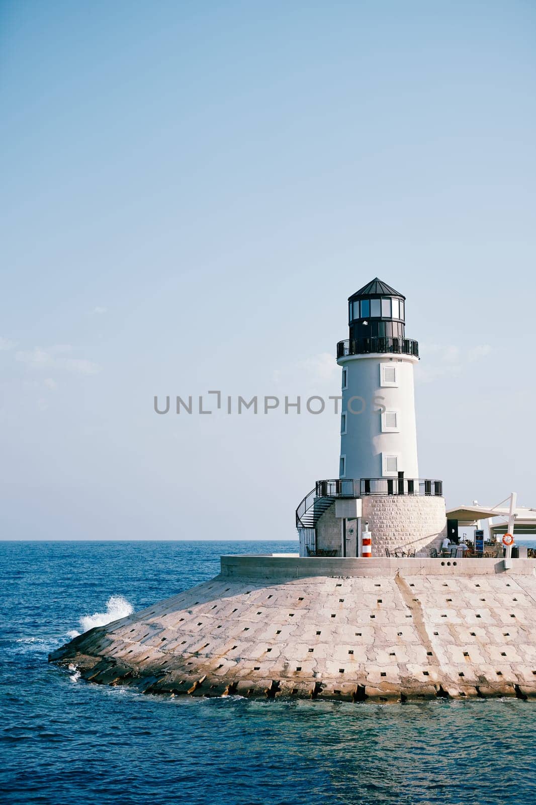 Lighthouse on the breakwater in Lustica Bay. Montenegro by Nadtochiy