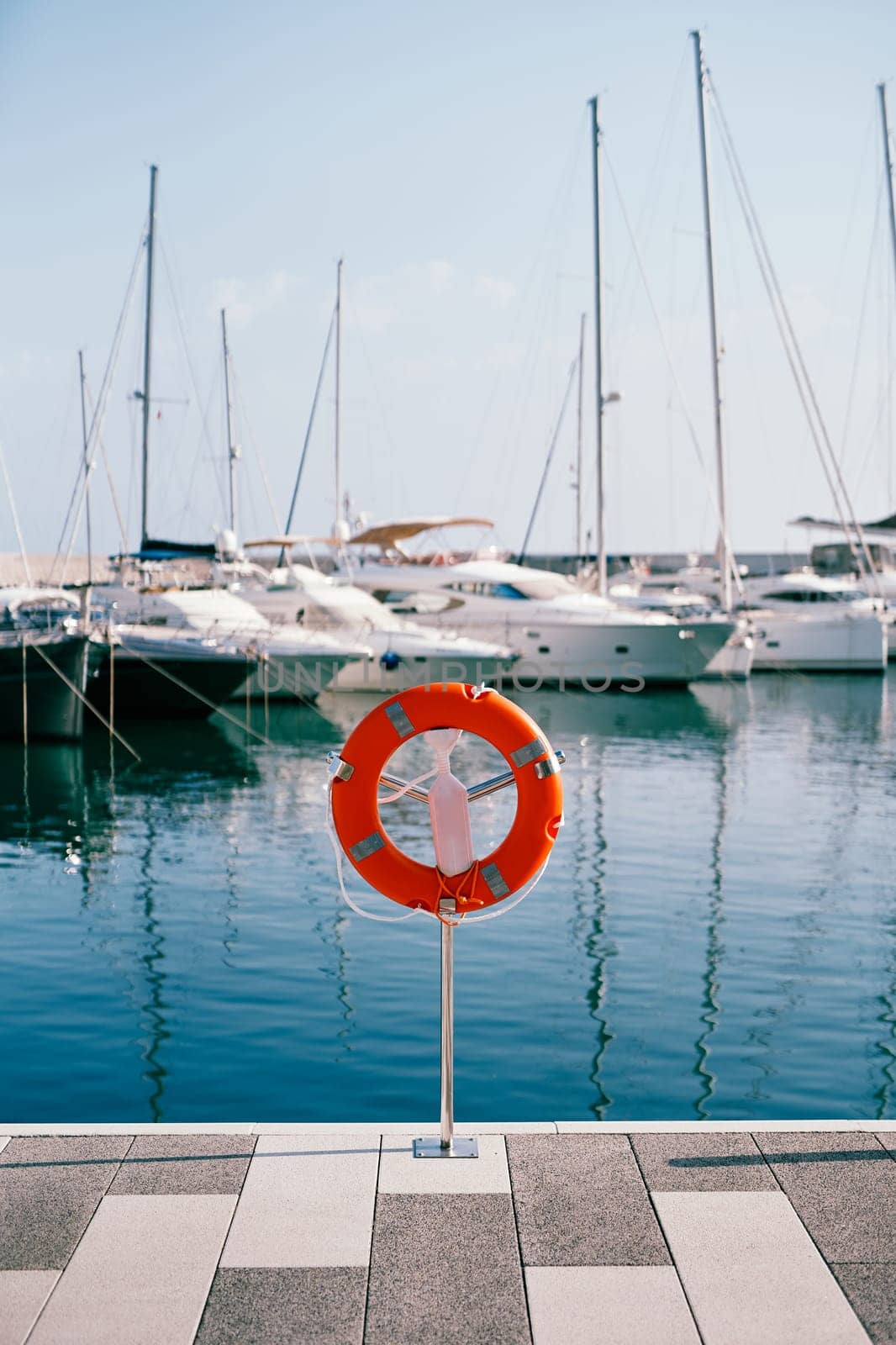 Red lifebuoy on a metal stand with a lock on the pier. High quality photo
