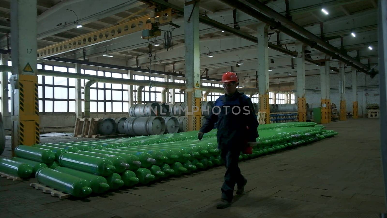 Worker in uniform and helmet at industrial plant. Clip. Man in uniform works at factory. Professional worker at industrial or power plant.