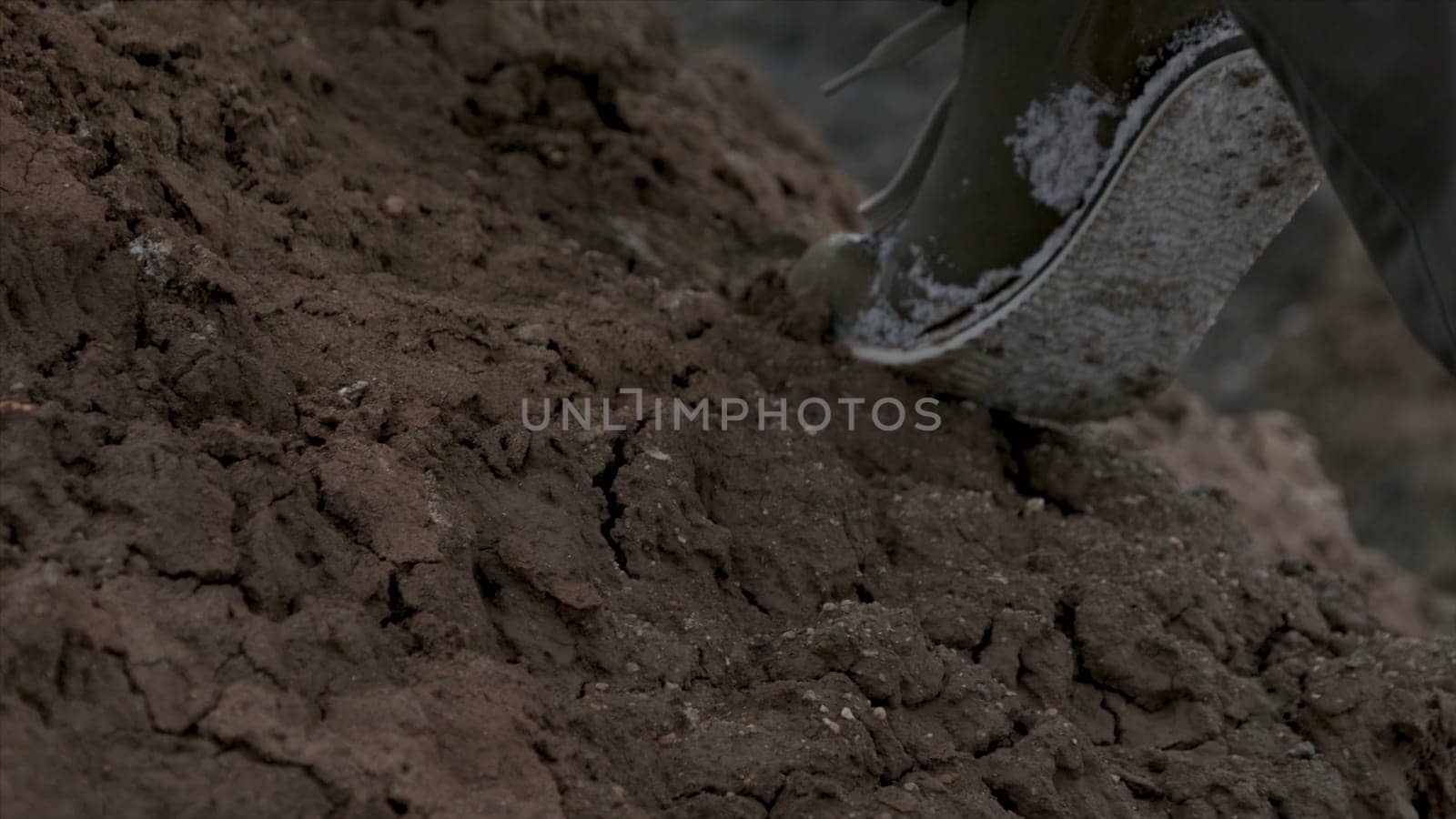 Close up of hiking boots and legs climbing up rocky trail. Close up climber legs make a last steps before peak. Close up of man foot in the moutain.