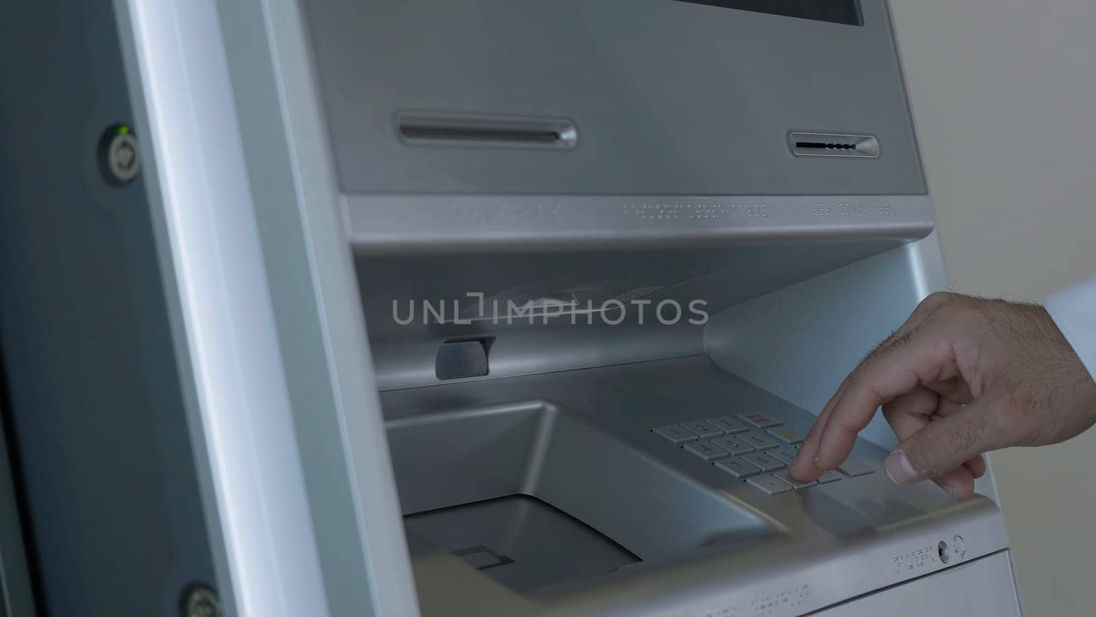 Male hand entering pin code on ATM keyboard, withdrawing money from account. HDR. Automatic machine for cash withdrawal