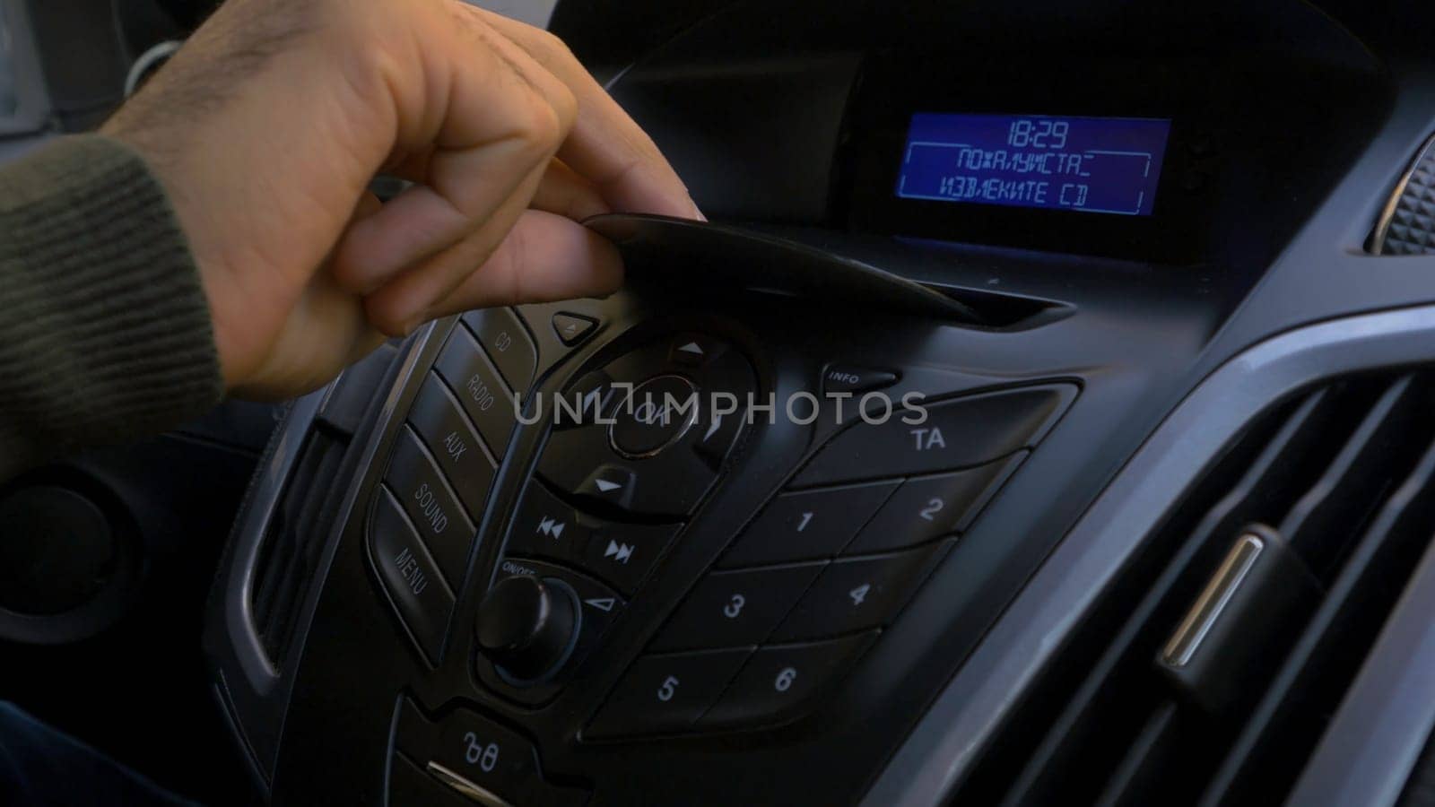 Man's hand puts the disk into the car player. Button control for compact disk player in a car. Hand puts the disk into the radio car HD