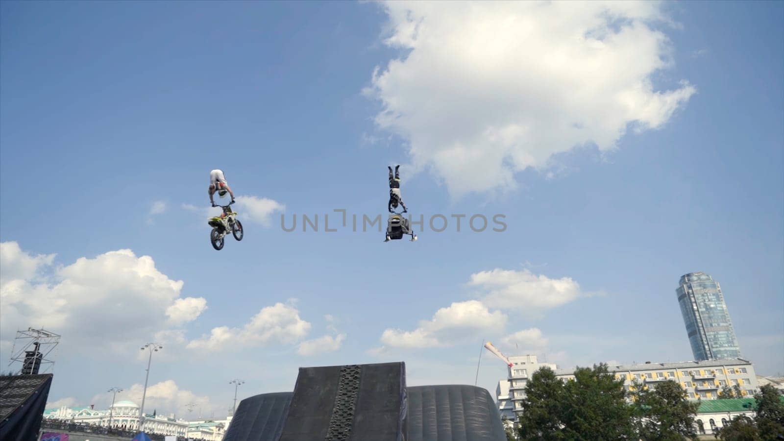 Motorcyclist performs stunts with jump in Moto festival. Action. Performance with motorcycle and snowmobile on springboard of Moto festival.