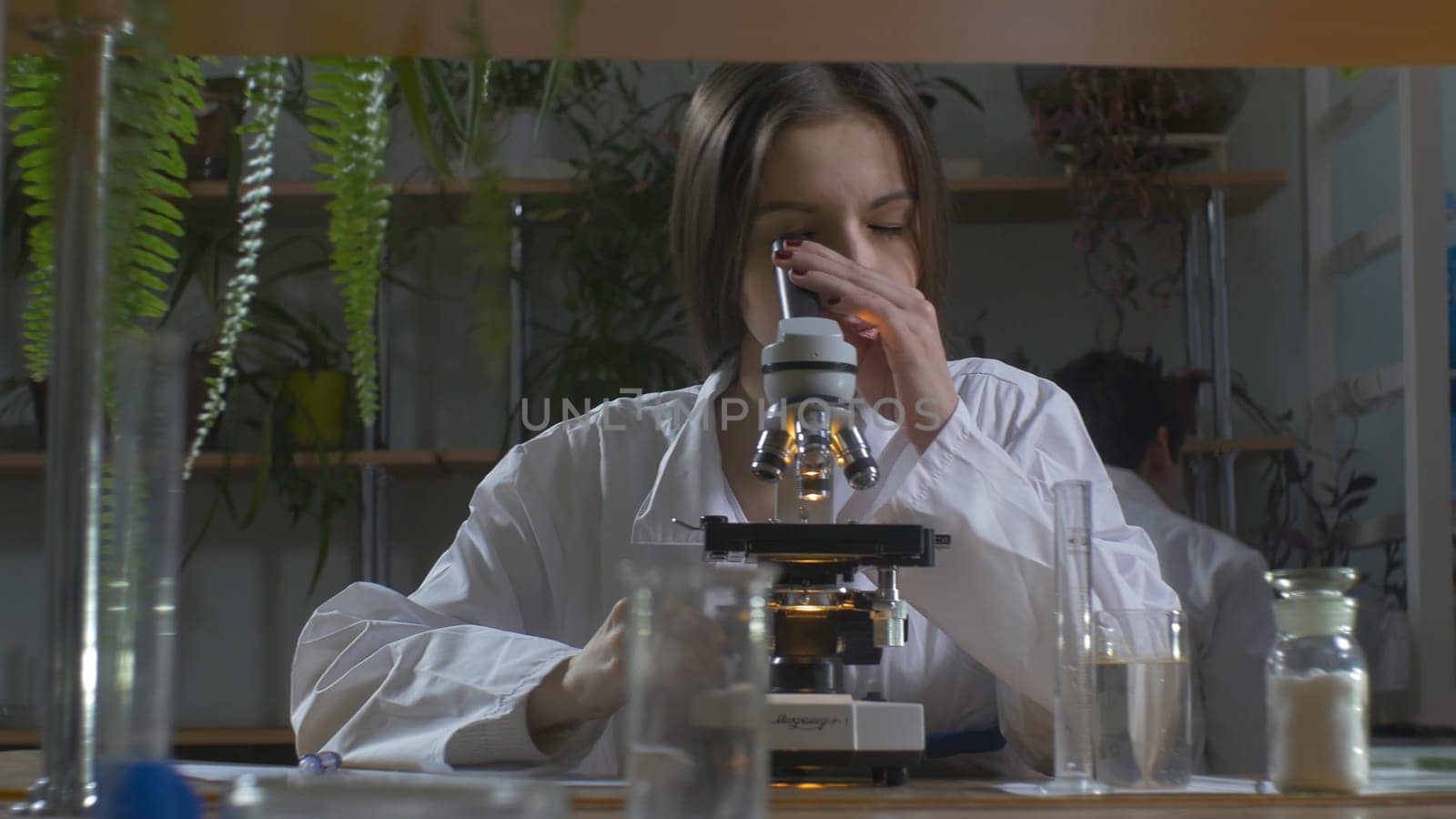 Young scientist looking through a microscope in a laboratory. Young scientist doing some research.