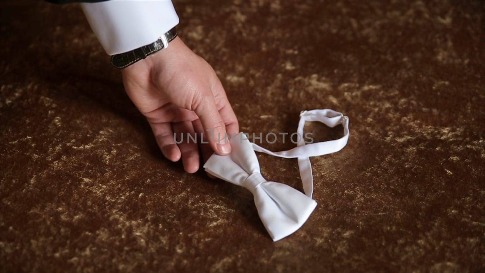 Groom's hand takes a bow tie. Preparing to wedding day. The man takes the bow-tie. Wedding accessories. Groom holding brown bow tie in his hand. Man holding bow tie. Elegant gentleman clother. Wedding HD