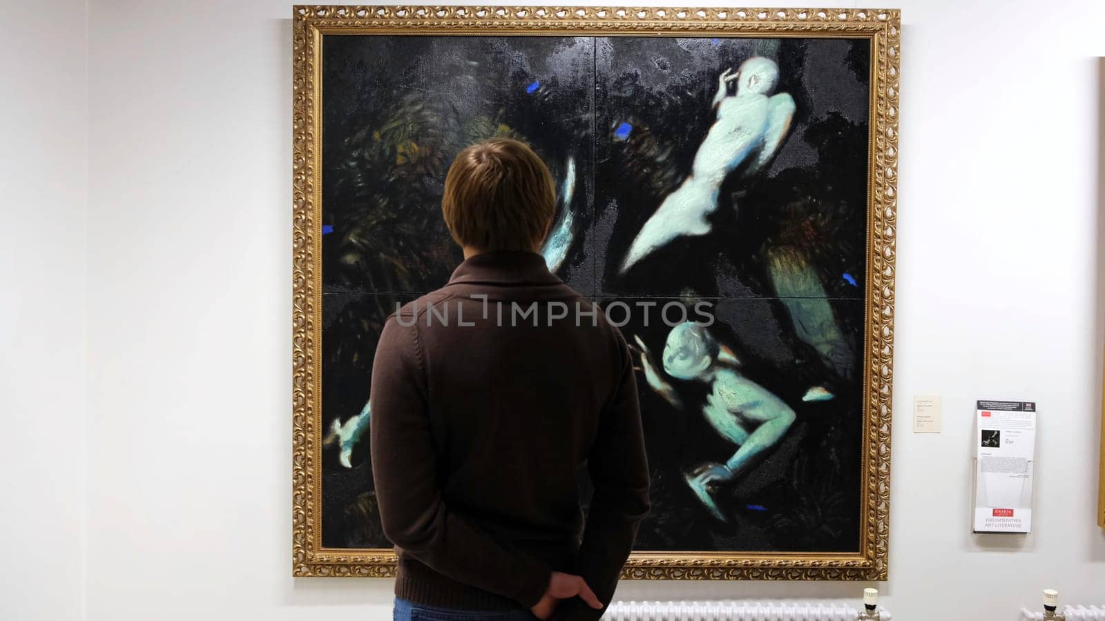 Close-up of unknown man looking at the modern painting in the museum or gallery of modern art. Concept. View from the back by Mediawhalestock