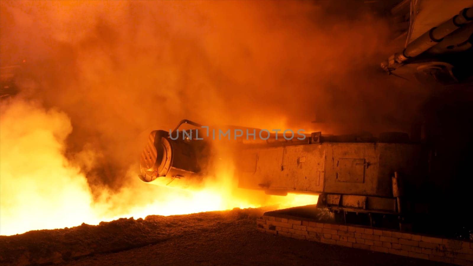 Molten steel pouring process with steam clubs at metallurgical plant. Close up fot steel pouring machine.