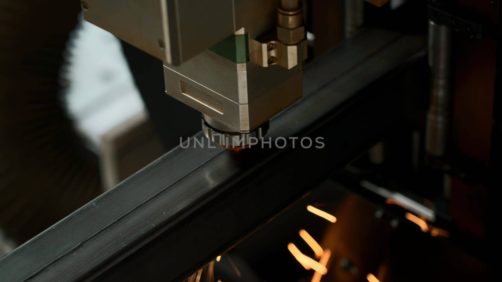 Laser cut head machine while cutting the sheet metal with the sparking light in factory. Creative. Process of laser engraving on metal