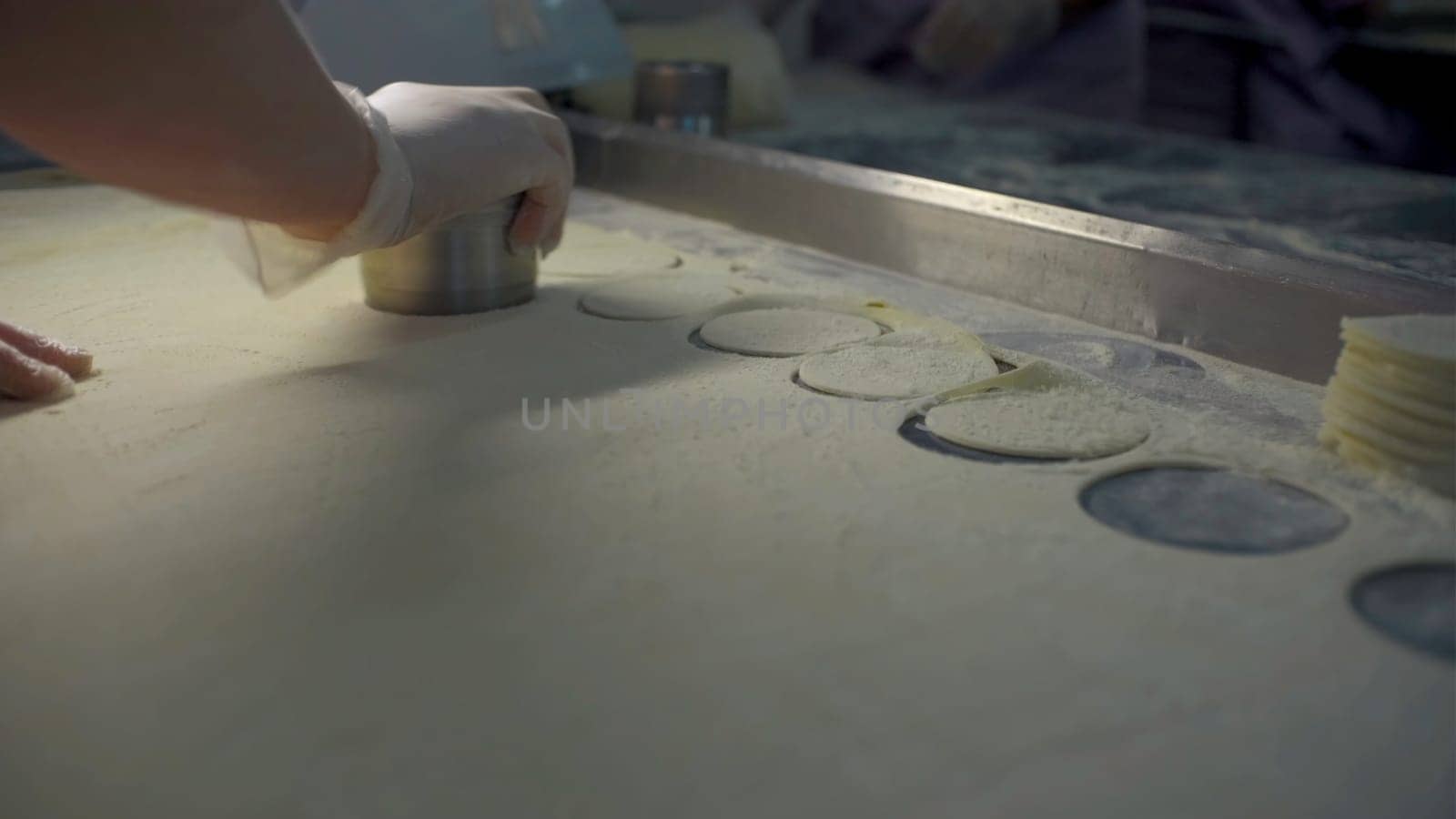 Close-up of slicing dough for dumplings. Clip. Cook quickly makes dumpling molds. Round cutting of dough for large number of dumplings.