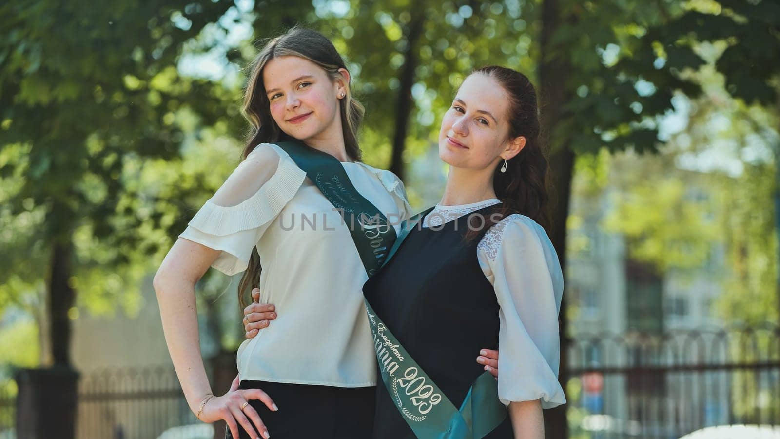 Russian girls graduate posing with a flyer and inscription - Graduate 2023 on graduation day. by DovidPro