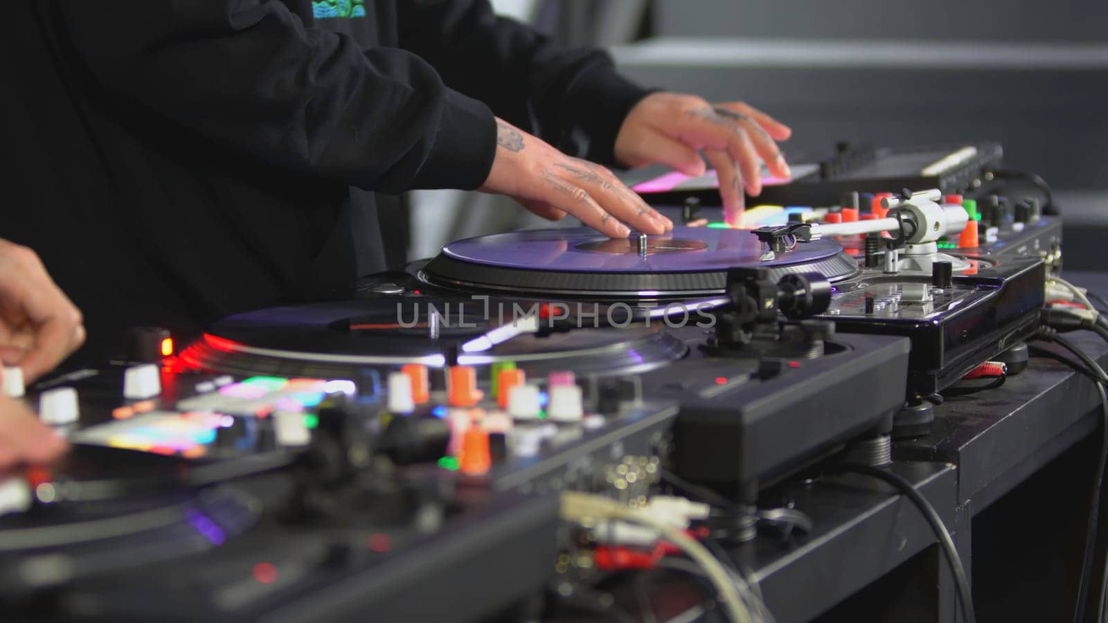 DJ spinning record at disco. Art. Close-up of DJ's hand on mixer. Glowing music panel at party. Musician's work in nightclub.