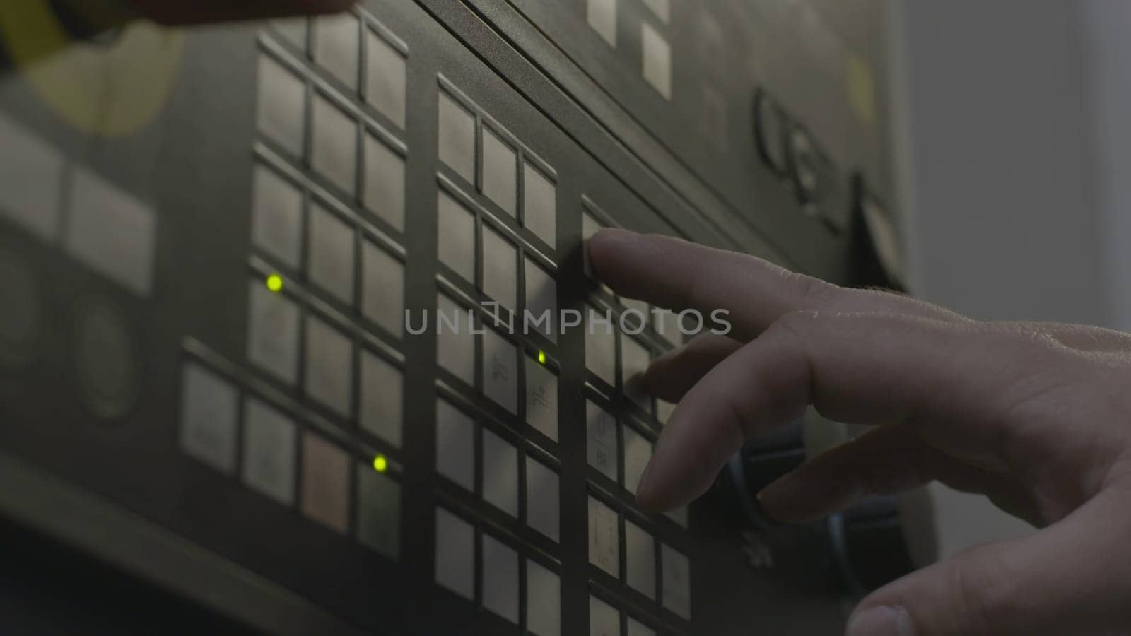 Close up of a hand presses buttons on the control panel of industrial equipment. Side view of male hand pushing the button at the factory panel.