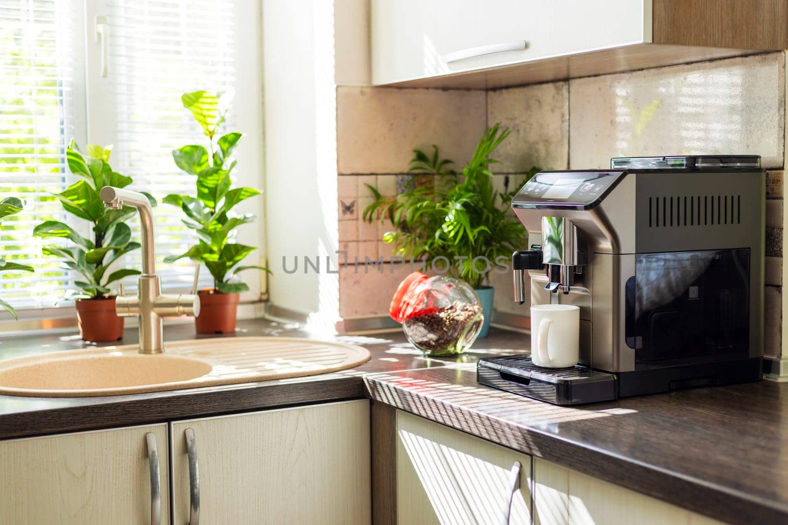 Modern electric coffee machine with cup on countertop in kitchen.