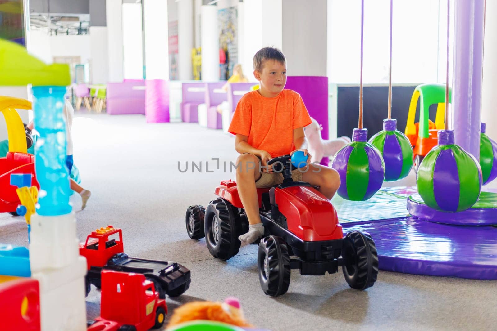 A child rides a toy pedal car at a children's play center by andreyz