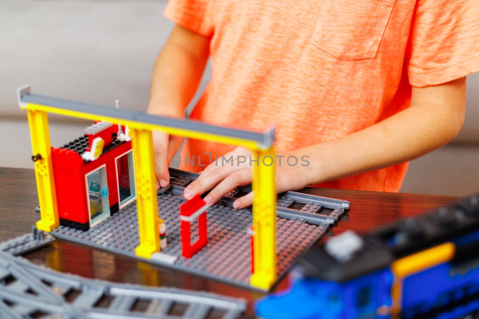 Child boy playing and building with colorful plastic bricks at the table by andreyz