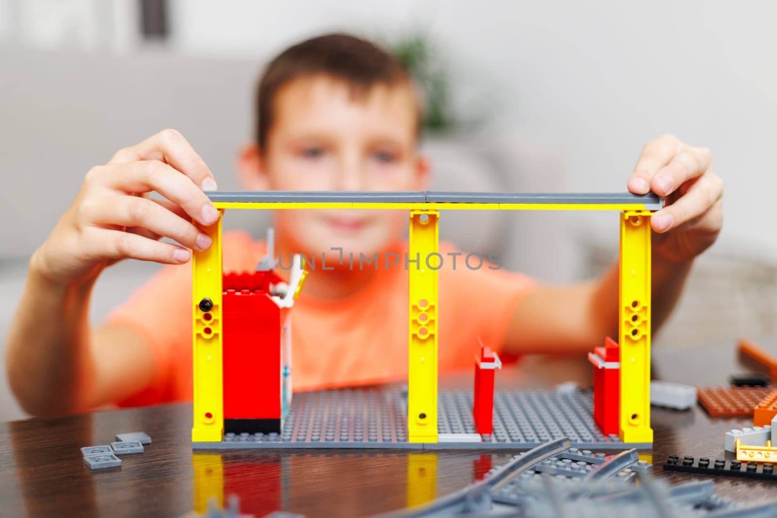 Child boy playing and building with colorful plastic bricks at the table by andreyz