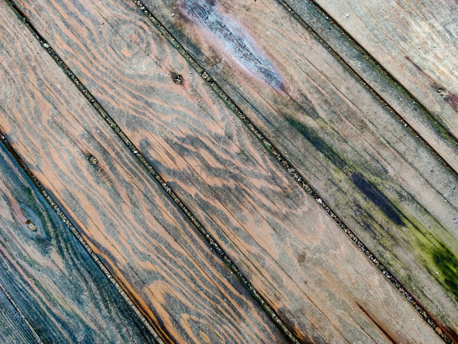 Surface of wooden boards with multicolored spots from dampness, diagonal lines, top view.