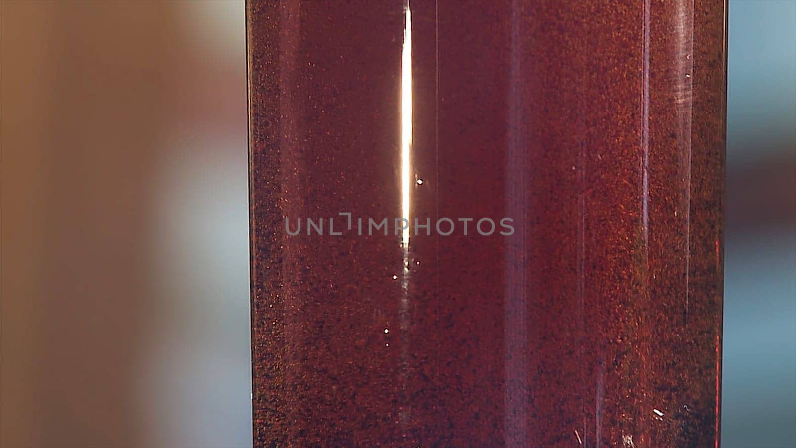 Gas bubbles float in a plastic bottle with dark blue liquid. Red liquid with bubbles in plastic bottle close up view.