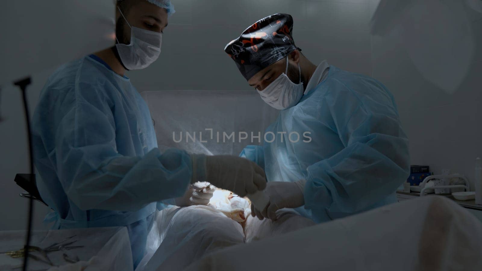 Operation process in medical clinic. Action. Specialists perform an operation, using medical instruments in operating room