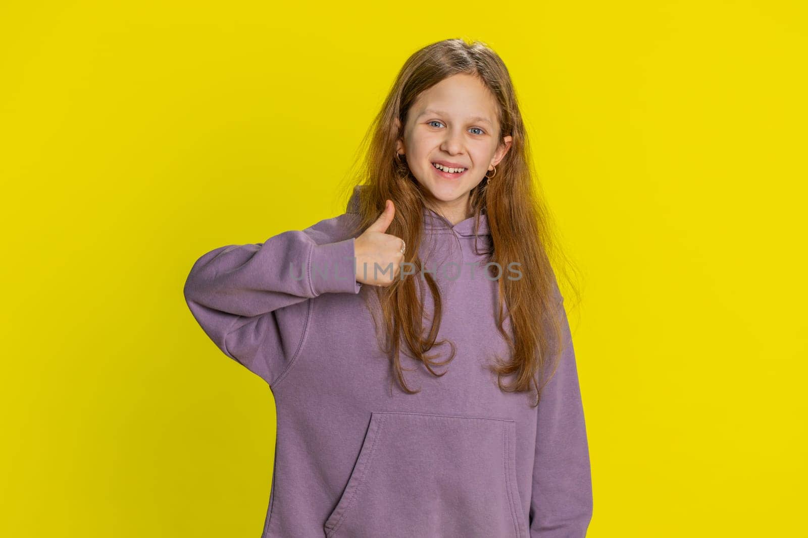 Like. Happy young preteen child girl kid looking approvingly at camera showing thumbs up, like sign positive something good, positive feedback great news. Children isolated on studio yellow background