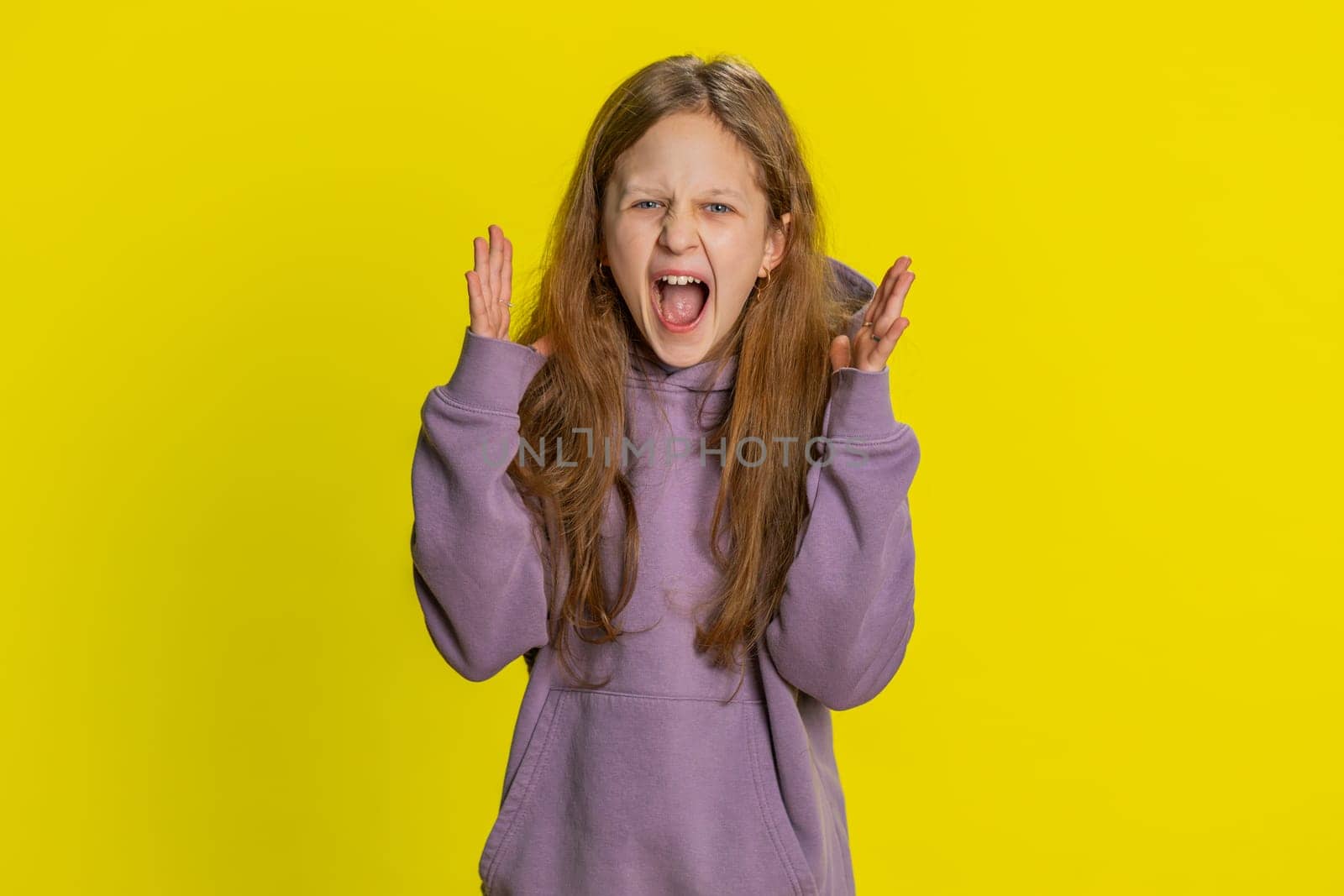 Irritated angry preteen child girl kid scream from stress tension problems feels horror hopelessness fear surprise shock expresses rage nervous quarrel. Teenager children isolated on yellow background