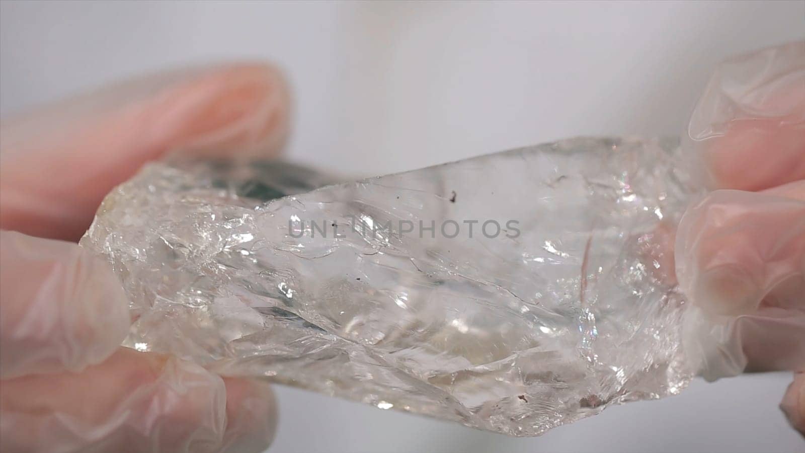 Scientist holding sample of raw crystal in hands. Male hand holding a fragment of rock crystal mineral.