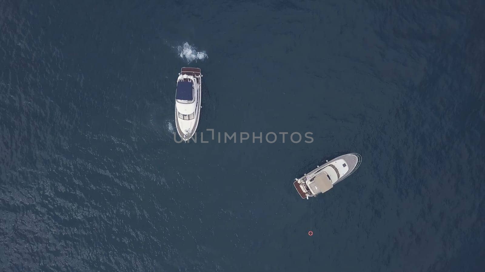 Amazing aerial top view of two yachts and swimming friends in dark blue water. People having fun in caribbean paradise sea near new sailing boats.