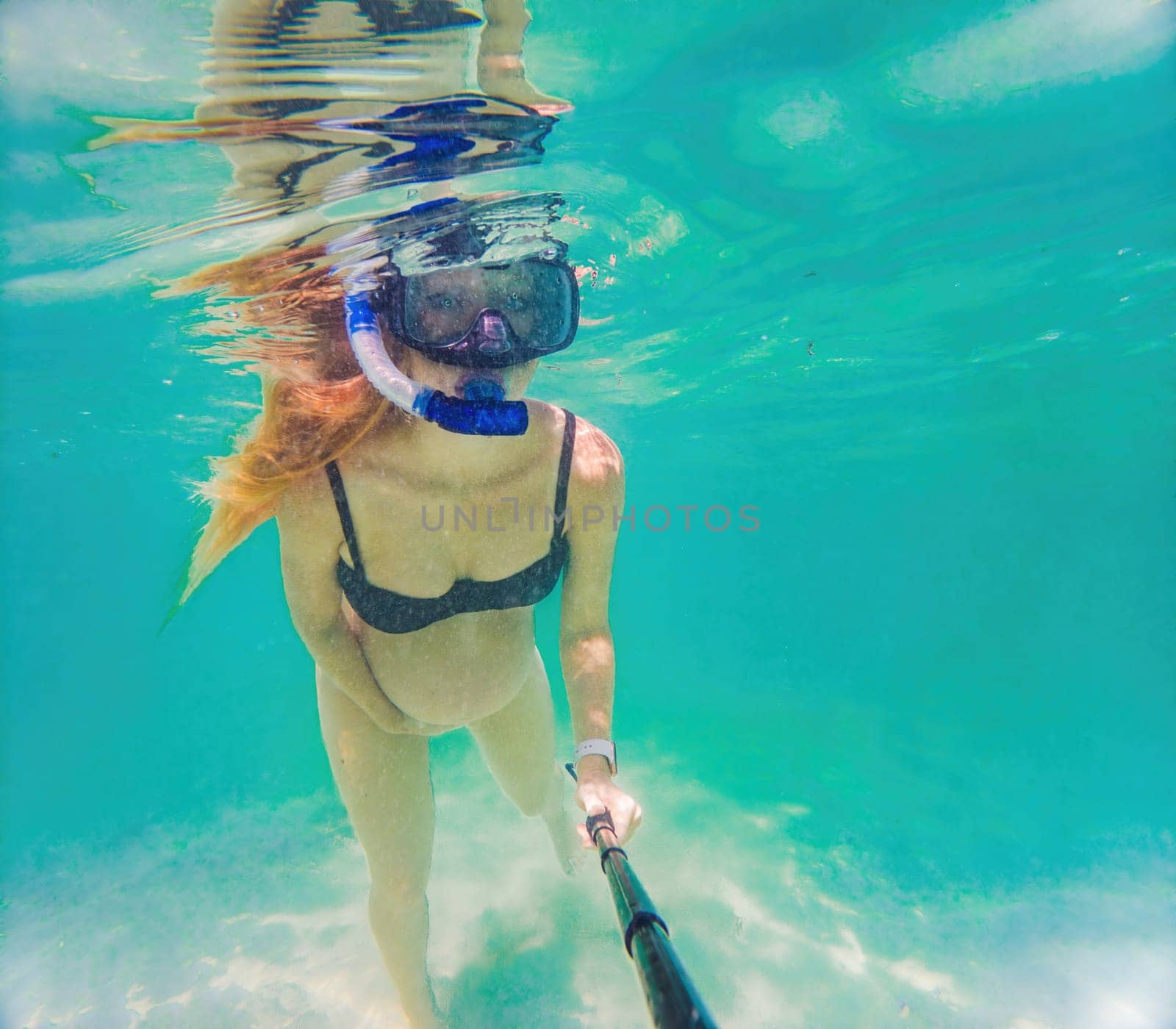 In an ethereal underwater scene, a pregnant woman gracefully floats, embodying the beauty of maternity beneath the tranquil surface of the sea.