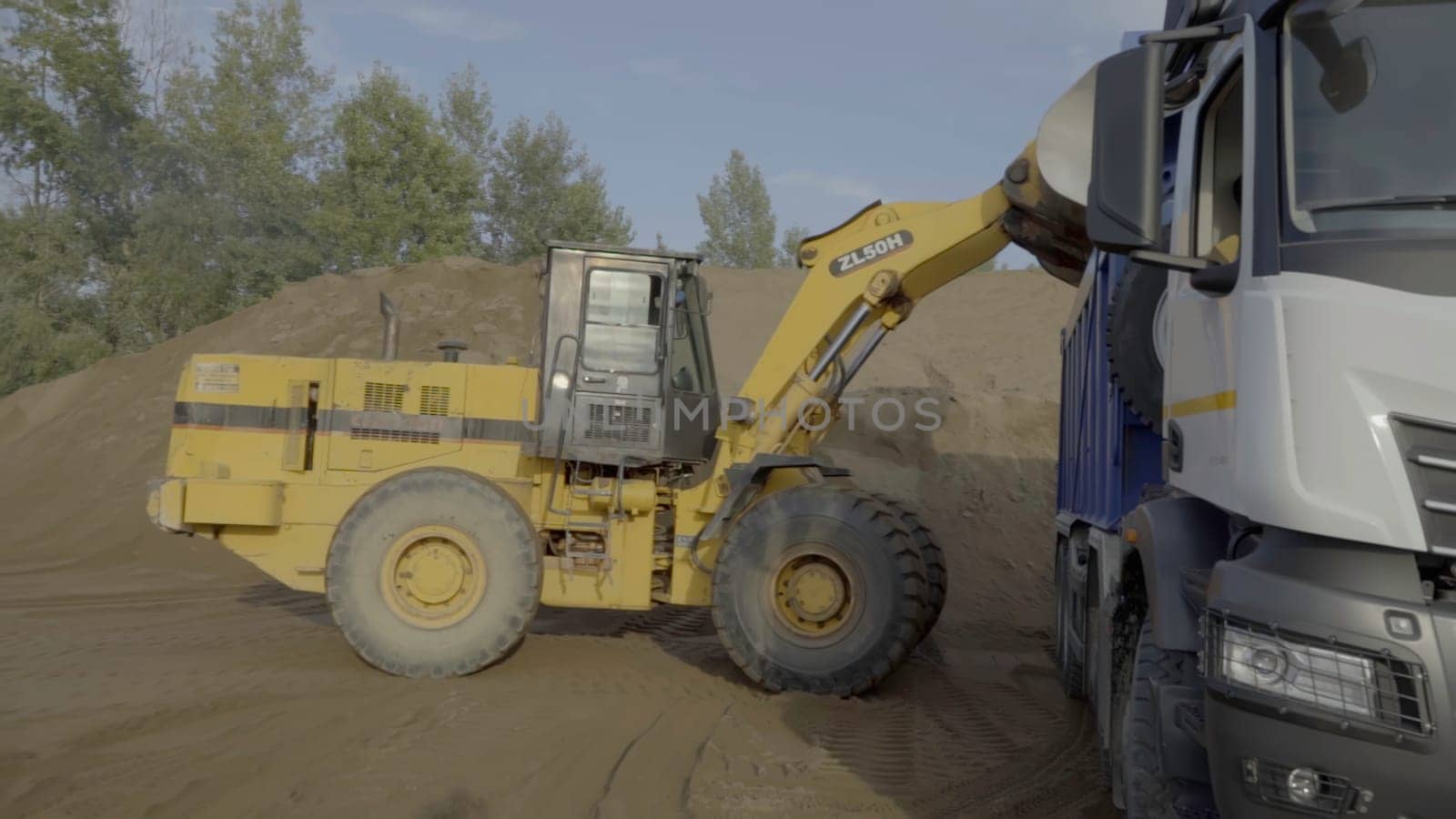 Berlin, Germany - June 20, 2022: Different machines work at a stone quarry. Scene. Industrial background with tractors and trucks loading stones and sand