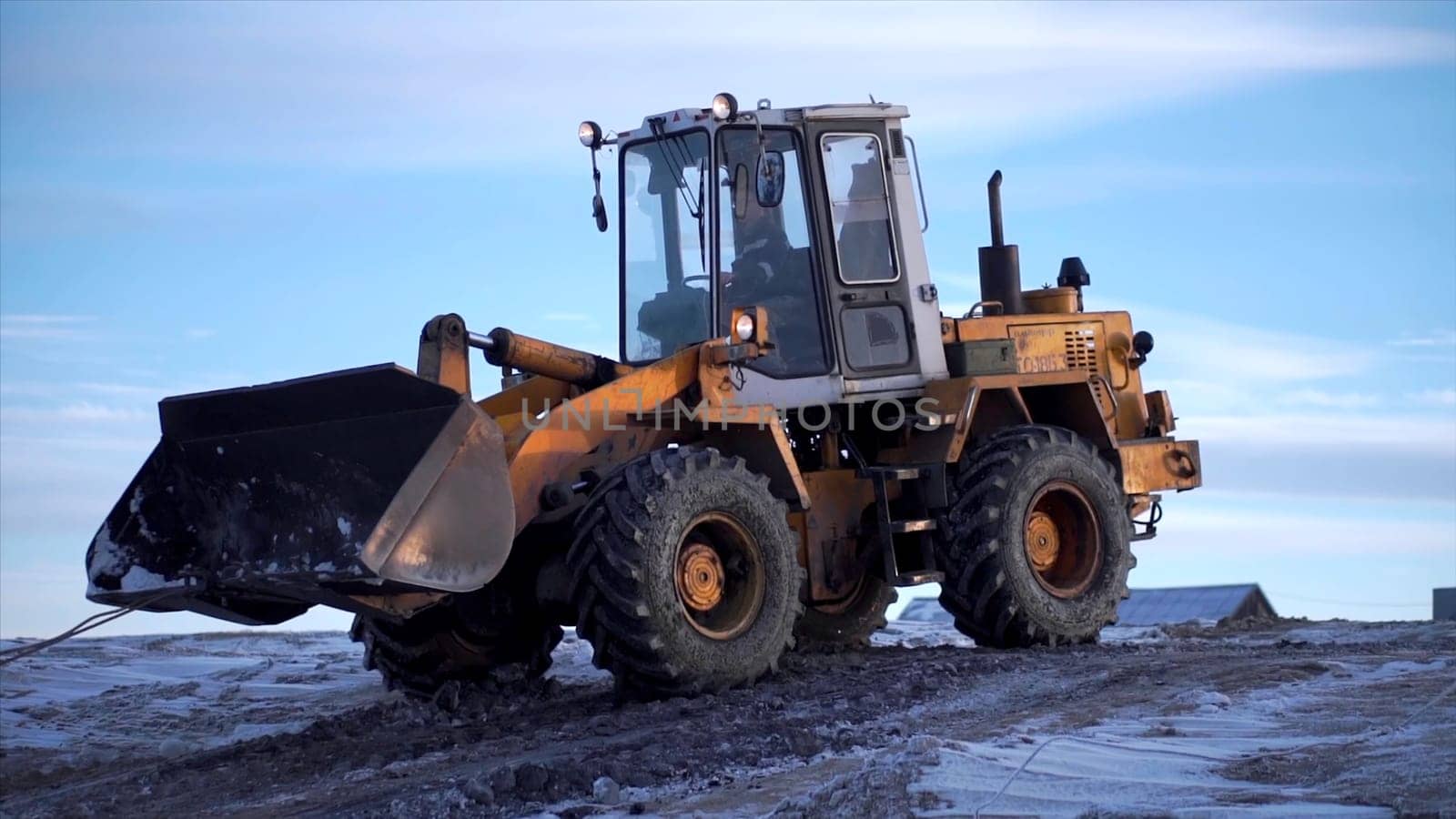 Snowy weather, excavator digging frozen ground. Clip. Heavy industry concept, machine at mine work on blue sky background