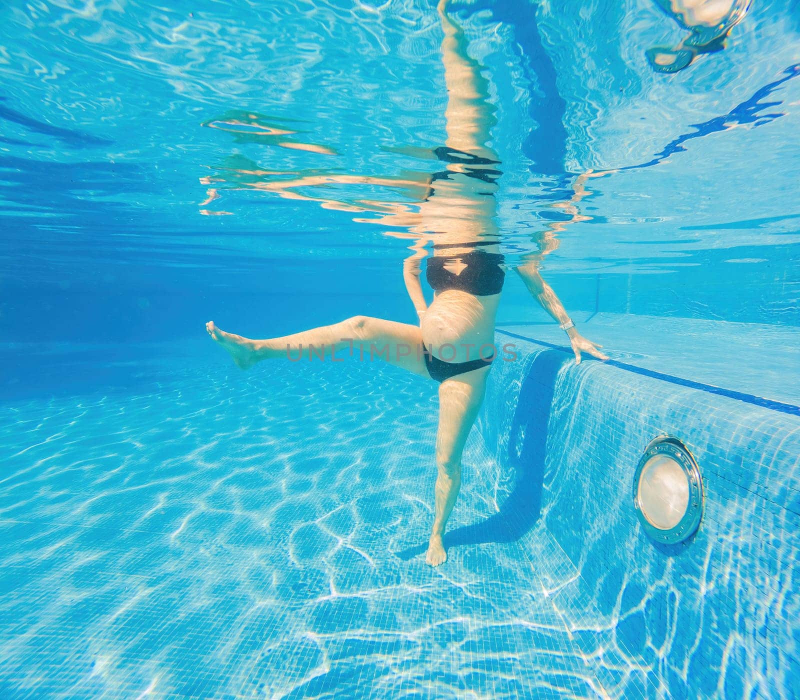 Embracing aquatic fitness, a pregnant woman demonstrates strength and serenity in underwater aerobics, creating a serene and empowering image in the pool.