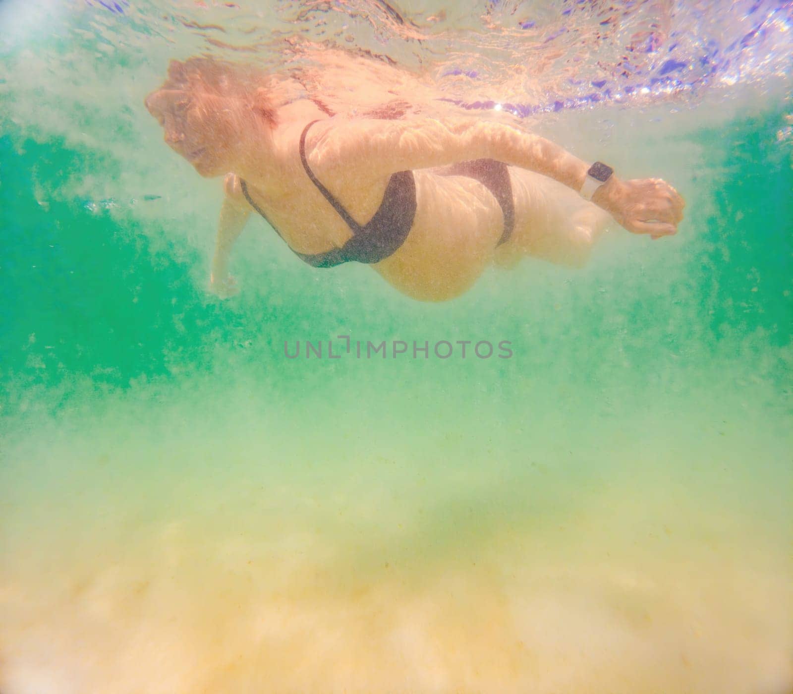 In an ethereal underwater scene, a pregnant woman gracefully floats, embodying the beauty of maternity beneath the tranquil surface of the sea.