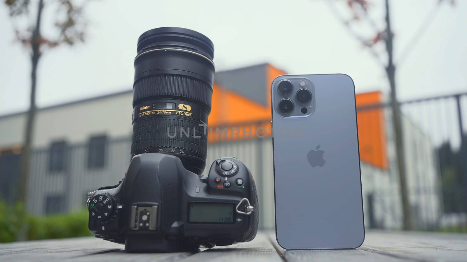 RUSSIA, MOSCOW - SEPTEMBER 27, 2021: Camera and phone comparison. Action. Professional camera with lens or new iPhone. Comparison of cameras of new iPhone 13 pro with professional camera.