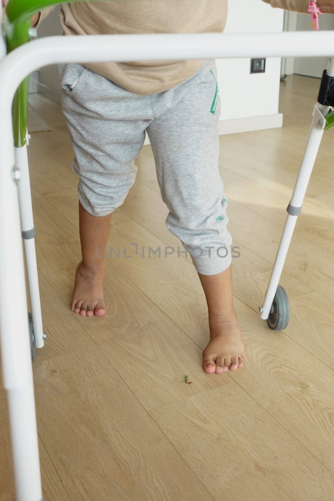 child with walking frame and knee orthosis at home .