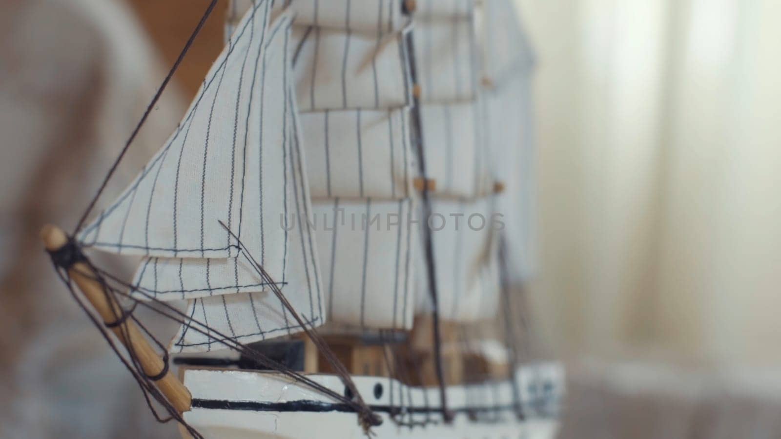Close-up of the little marine white ship model from the wood on a striped background on the blurred light background. Hobby and collecting concept