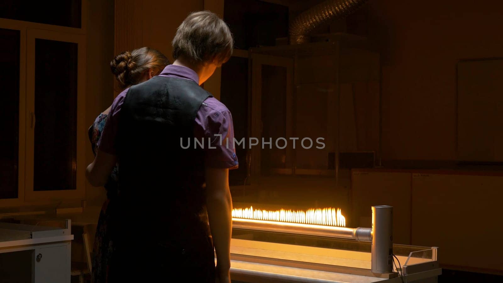 Students look at the flame in the lab. Students conduct an experiment.